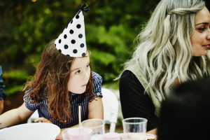 Young girl wearing party hat leaning on table